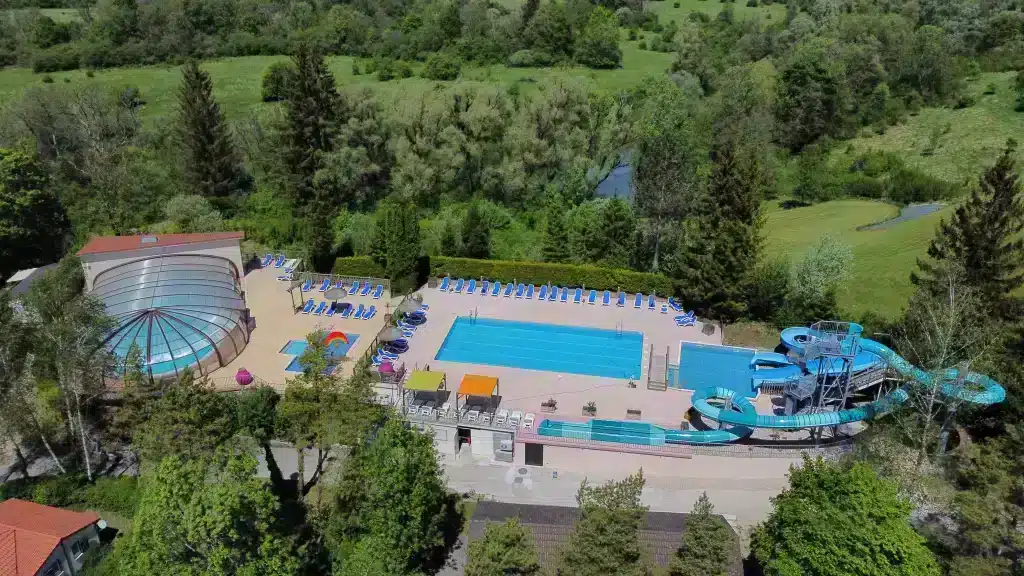 Vue sur la piscine extérieure chauffée du Camping Le Moulin dans le Jura